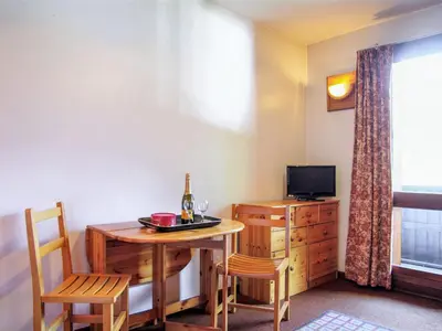 a room with a table and a television and a table and chairs at Apartment Les Periades by Interhome in Chamonix-Mont-Blanc