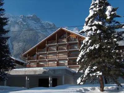 a building with a snow covered mountain in the background at Apartment Les Pècles by Interhome in Chamonix-Mont-Blanc