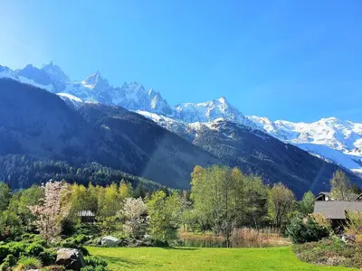 a house in a field with mountains in the background at La Cordée - Charmant Appartement – 4 personnes in Chamonix-Mont-Blanc