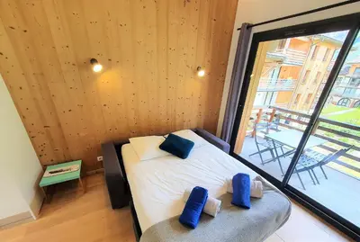 a bedroom with a bed with two blue pillows on it at La Cordée - Charmant Appartement – 4 personnes in Chamonix-Mont-Blanc