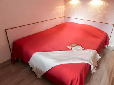 a red bed with a book on it in a room at Apartment Jonquilles-7 by Interhome in Chamonix-Mont-Blanc