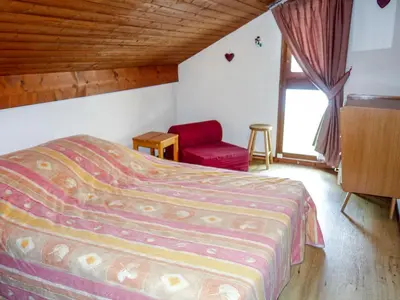 a bedroom with a bed and a red chair at Apartment Le Brûlaz by Interhome in Les Contamines-Montjoie