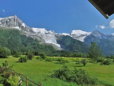 a grassy field with snowy mountains in the background at Holiday Home Les Pelarnys by Interhome in Chamonix-Mont-Blanc