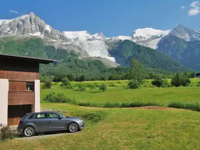 a car parked in front of a house with mountains at Holiday Home Les Pelarnys by Interhome in Chamonix-Mont-Blanc