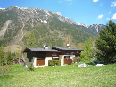 a house in a field with a mountain in the background at Holiday Home Les Pelarnys by Interhome in Chamonix-Mont-Blanc