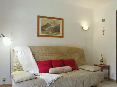 a living room with a couch with red pillows at Studio Les Chamois by Interhome in Les Houches