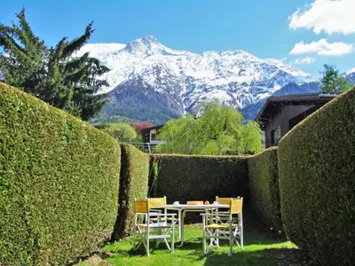a table and chairs in a garden with a snow covered mountain at Studio Les Chamois by Interhome in Les Houches