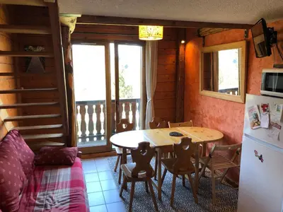 a kitchen with a table and a refrigerator at LES CARROZ LE LAYS cosy apartment 40M2 vue montagne plein sud in Les Carroz d'Araches