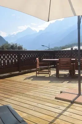 two benches on a deck with a table and an umbrella at Spacious Apartment 2 Minutes from Ski Lift, Equipped for Babies in Les Houches