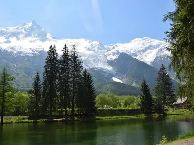 a body of water with snow capped mountains in the background at Spacious Apartment 2 Minutes from Ski Lift, Equipped for Babies in Les Houches