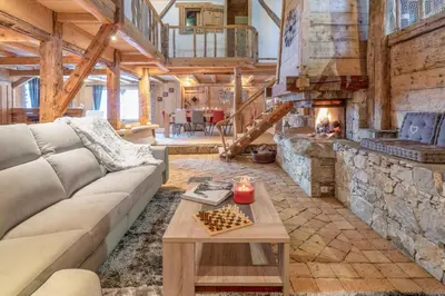 a living room with a couch and a stone fireplace at Le Charmélie 1600 in Flaine