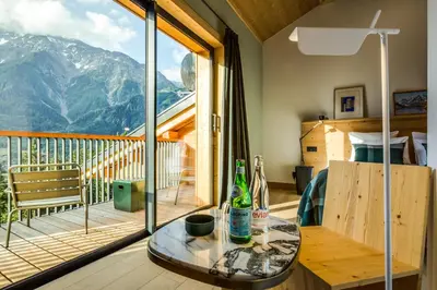 a room with a table and a balcony with mountains at Le Chalet Mont Blanc in Les Houches