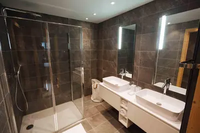 a bathroom with a shower and two sinks and a glass shower stall at Megeve Appartment – Vacances d'hiver – АЕ102 in Megève