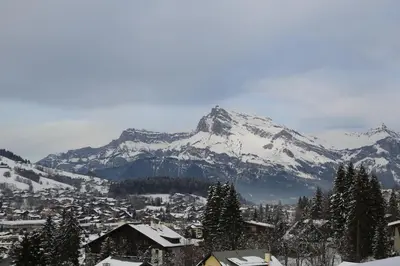 a snow covered mountain in front of a town with houses at Residence Lesporting Ski – Megeve – АW201 in Megève