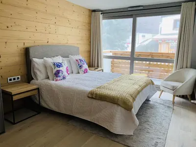 a bedroom with a bed and a large window at Residence Lesporting Ski – Megeve – АW201 in Megève