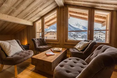 a living room with two chairs and a table and windows at Chalet Yolo - Chalet Retreat in Central Chamonix Steam Room in Chamonix-Mont-Blanc