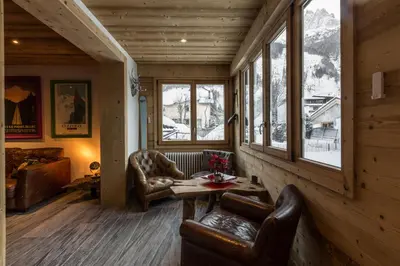 a living room with chairs and a table and windows at Chalet Yolo - Chalet Retreat in Central Chamonix Steam Room in Chamonix-Mont-Blanc