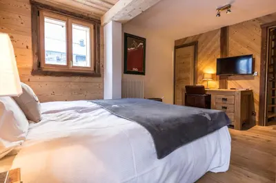 a bedroom with a large bed and a television at Chalet Yolo - Chalet Retreat in Central Chamonix Steam Room in Chamonix-Mont-Blanc