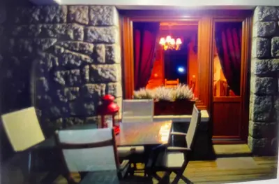 a dining room with a table and chairs and a stone wall at Appartement l'Edelweiss in Megève