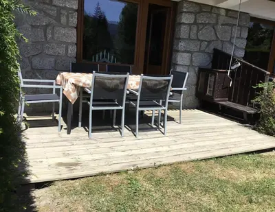 a wooden deck with a table and chairs on it at Appartement l'Edelweiss in Megève
