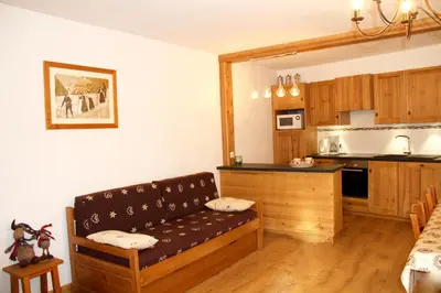 a living room with a couch and a kitchen at Maison Salina in Samoëns