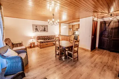 a living room with a table and chairs and a kitchen at Maison Salina in Samoëns
