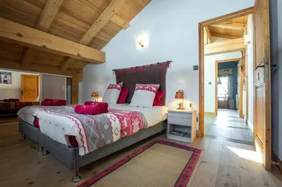 a bedroom with a large bed with red pillows at Le CHALAY in Les Carroz d'Araches