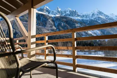 a chair on a porch with a view of mountains at La Cordee 331 Apartment in Chamonix-Mont-Blanc