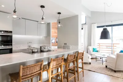 a kitchen and living room with a counter and chairs at La Cordee 331 Apartment in Chamonix-Mont-Blanc