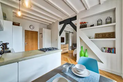 a kitchen with white cabinets and a table and blue chairs at Marie Paradis Studio Apt 15 in Chamonix-Mont-Blanc
