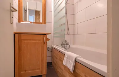 a bathroom with a tub and a sink and a mirror at Apartment Grepon 3A - A Central Chamonix Haven in Chamonix-Mont-Blanc