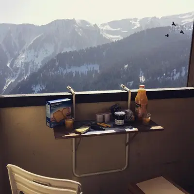 a table on a balcony with a view of a mountain at Les Cimes in Samoëns