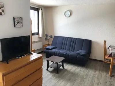 a living room with a blue couch and a tv at Les Cimes in Samoëns