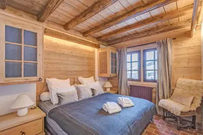 a bedroom with a bed and a chair in a room at Chalet Les Meuniers in Megève