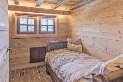 a bed in a wooden room with a window at Chalet Les Meuniers in Megève