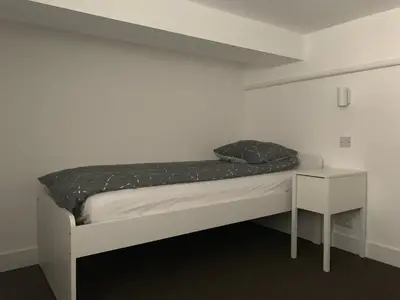a bed in a white room with a night stand at Le Mont Joly in Saint-Gervais-les-Bains