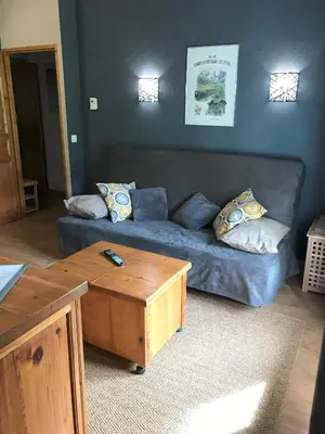 a living room with a blue couch and a coffee table at Appartement T2+cabine indépendante au départ des télécabines Saint-Gervais/Bettex/Mont d’Arbois in Saint-Gervais-les-Bains