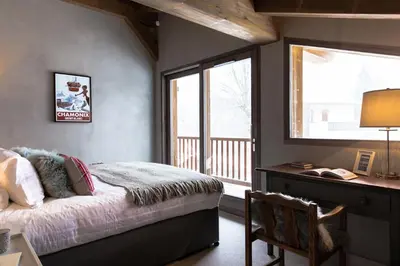 a bedroom with a bed and a desk and a window at Chalet Seren in Chamonix-Mont-Blanc