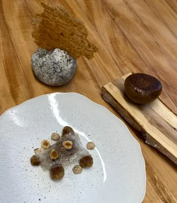 a white plate with some food on a wooden table at Hôtel Restaurant La Ferme de Cupelin in Saint-Gervais-les-Bains