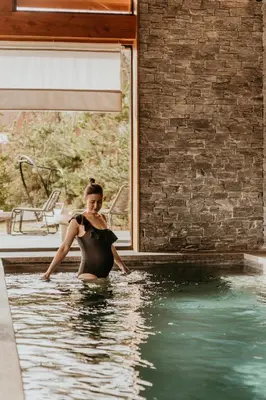 a woman is standing in a swimming pool at Hôtel Restaurant La Ferme de Cupelin in Saint-Gervais-les-Bains