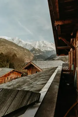 a roof of a building with mountains in the background at Hôtel Restaurant La Ferme de Cupelin in Saint-Gervais-les-Bains