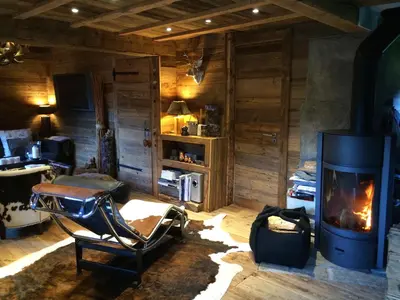 a living room with a fireplace and a chair at CHALET ALBA in Chamonix-Mont-Blanc