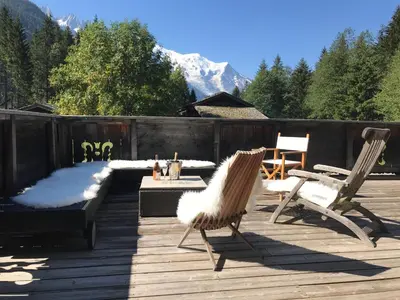 a deck with chairs and a table with a snow covered mountain at CHALET ALBA in Chamonix-Mont-Blanc