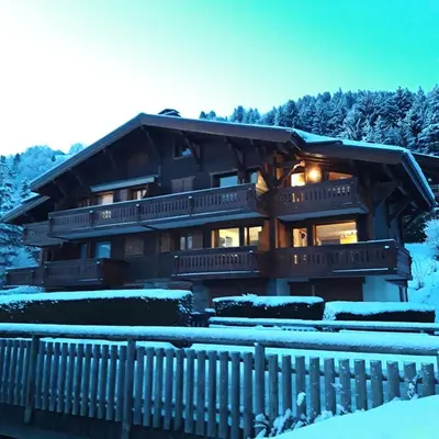 a house with snow covered mountains in the background at Les Fermes Mégevannes in Megève