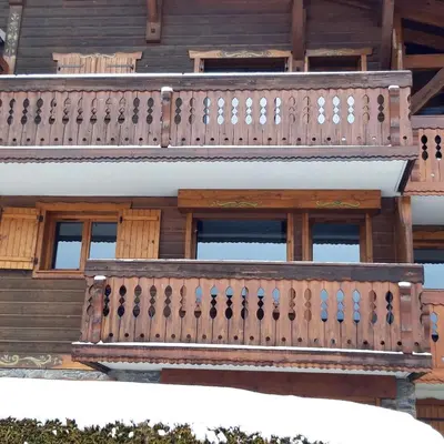 a pine tree in front of a building with mountains at Les Fermes Mégevannes in Megève