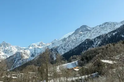 a snow covered mountain range with a cabin in the foreground at APARTMENT KANDAHAR - Alpes Travel - Central Chamonix - Sleeps 4 in Les Houches