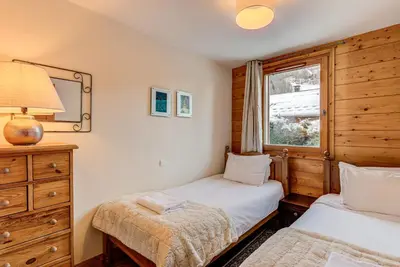 a bedroom with two beds and a mirror and a window at APARTMENT KANDAHAR - Alpes Travel - Central Chamonix - Sleeps 4 in Les Houches