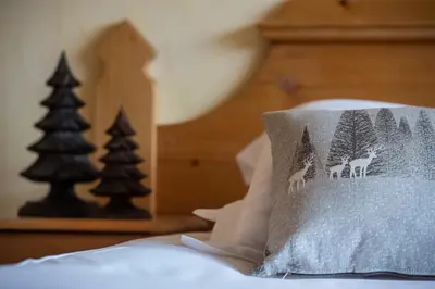 a pillow with deer in the forest on a bed at Le Chamois d'Or in Cordon