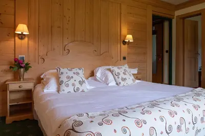 a bedroom with a large bed with white sheets and pillows at Le Chamois d'Or in Cordon
