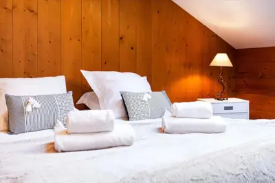 a large white bed with four pillows on it at Appartement Le Galetas des Planards in Chamonix-Mont-Blanc